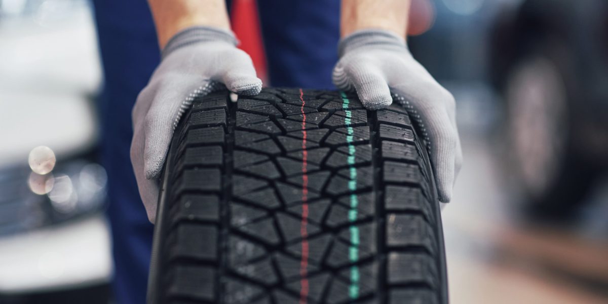 closeup-mechanic-hands-pushing-black-tire-workshop (1)